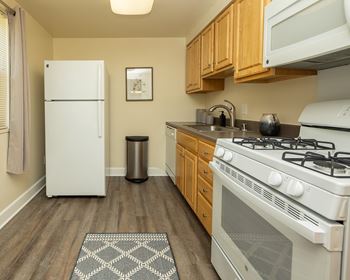 A kitchen with a white fridge, a white stove, and wooden cabinets.